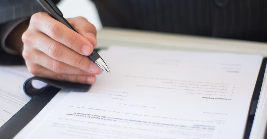 Close-up of a business professional signing documents in an office setting.