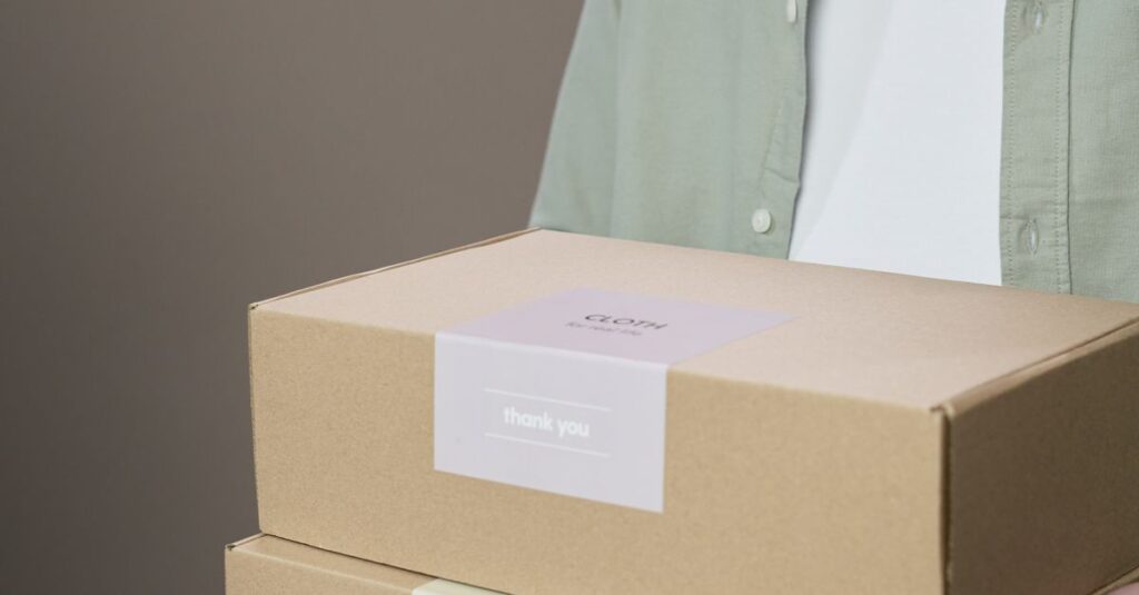 A person holding two labeled cardboard boxes against a neutral background.