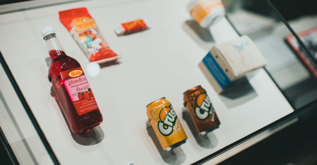Collection of drinks and snacks showcased in a glass display case, indoors.