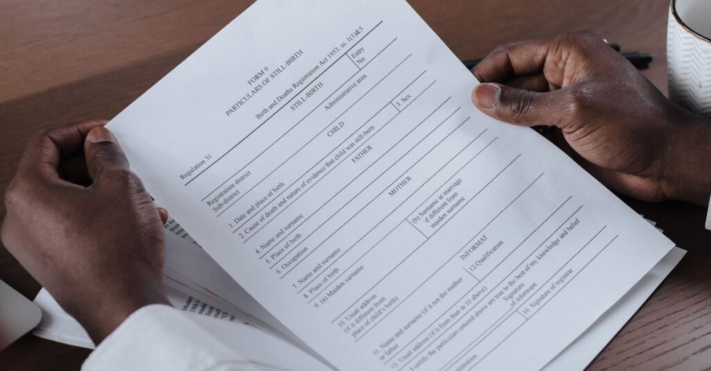 Close-up of a man holding and reviewing business documents at a wooden table.