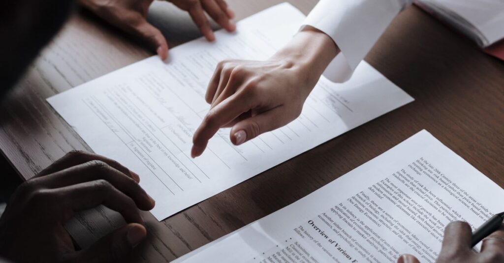 A professional business meeting with document signing, showing hands in action indoors.