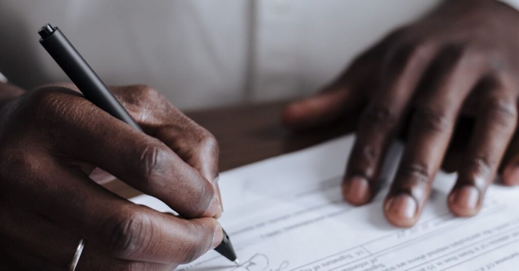 Close-up of a man signing legal documents at home, emphasizing responsibility.